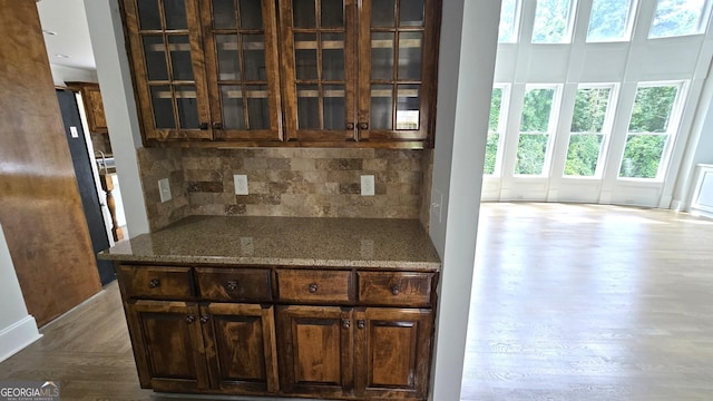 838 Natchez Valley Trce NE, Grayson, GA 30017 - kitchen featuring wood finished floors, decorative backsplash, glass insert cabinets, stone countertops, and dark brown cabinetry