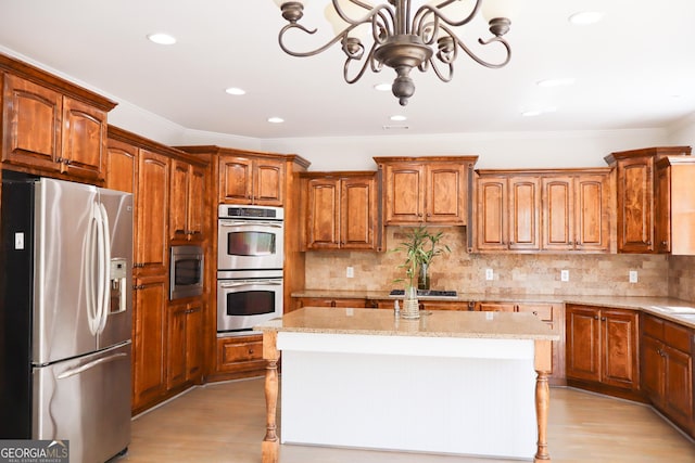 838 Natchez Valley Trce NE, Grayson, GA 30017 - kitchen featuring appliances with stainless steel finishes, a chandelier, light wood finished floors, a center island, and light stone countertops