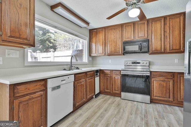 kitchen with brown cabinetry, stainless steel electric range, white dishwasher, a sink, and black microwave