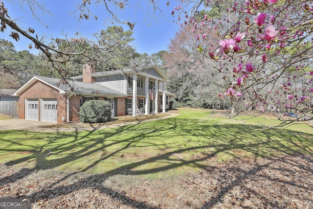 exterior space with driveway, a front lawn, an attached garage, brick siding, and a chimney