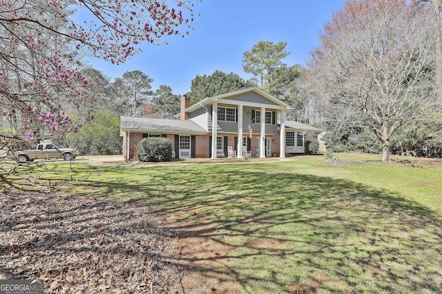 greek revival inspired property with a front lawn, a porch, brick siding, and a chimney