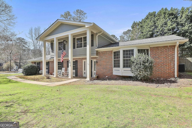 neoclassical home with brick siding, covered porch, and a front yard