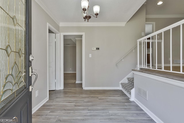 foyer with stairway, wood finished floors, visible vents, baseboards, and ornamental molding