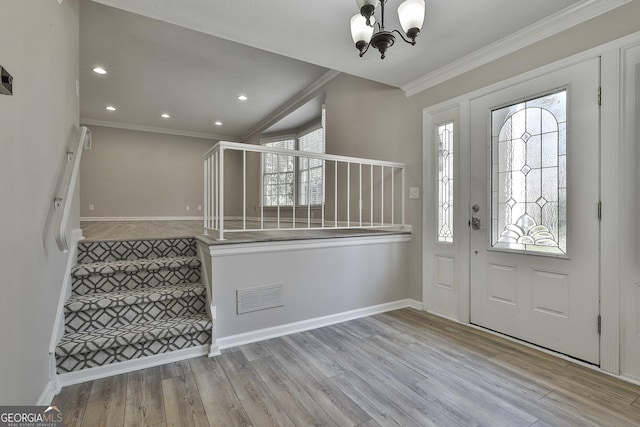 entryway with stairway, wood finished floors, visible vents, an inviting chandelier, and ornamental molding