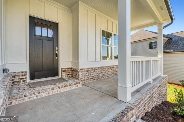 entrance to property featuring board and batten siding, brick siding, and covered porch