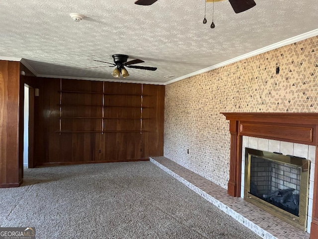 unfurnished living room with carpet, a ceiling fan, a tile fireplace, and ornamental molding