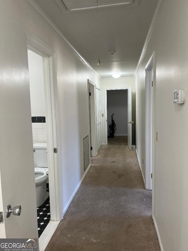 corridor with visible vents, concrete floors, crown molding, baseboards, and attic access