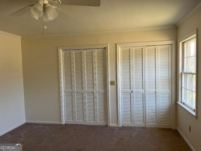 unfurnished bedroom with carpet flooring, baseboards, crown molding, and multiple closets