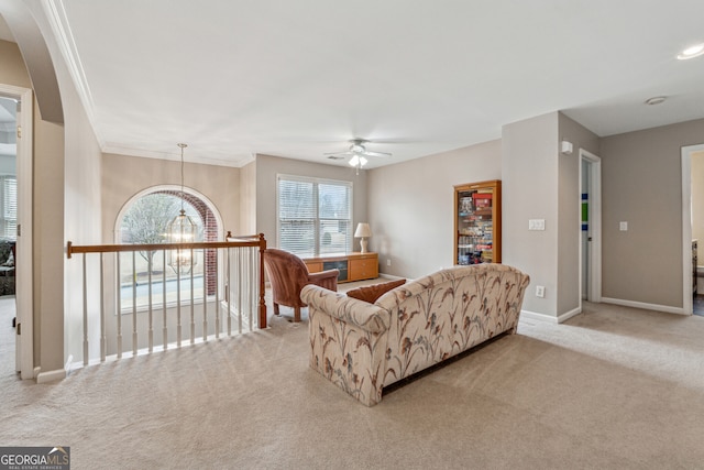 living area featuring baseboards, carpet floors, arched walkways, ornamental molding, and ceiling fan with notable chandelier