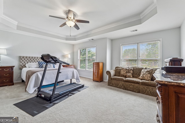 bedroom with a tray ceiling, light colored carpet, and visible vents