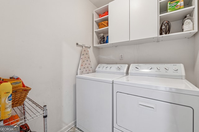 washroom featuring washing machine and clothes dryer, cabinet space, and baseboards