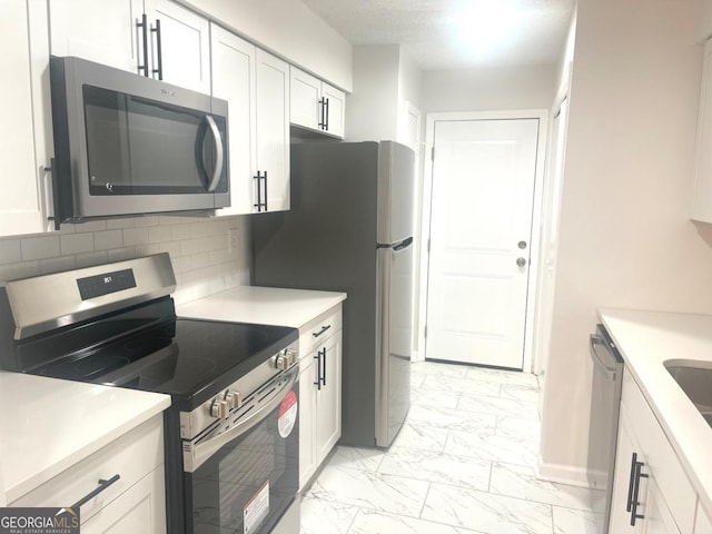 kitchen with marble finish floor, appliances with stainless steel finishes, white cabinets, and light countertops