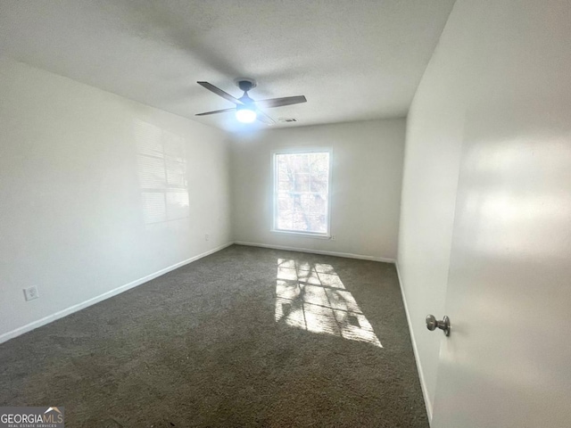 empty room with dark carpet, baseboards, and a ceiling fan