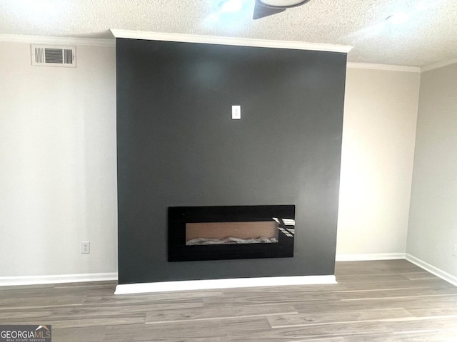 details featuring ornamental molding, wood finished floors, a textured ceiling, and visible vents