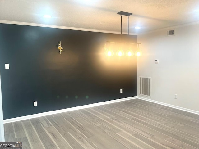 unfurnished room with baseboards, crown molding, wood finished floors, and visible vents