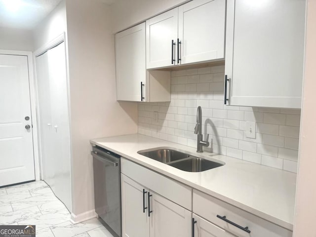 kitchen featuring marble finish floor, light countertops, dishwasher, a sink, and decorative backsplash