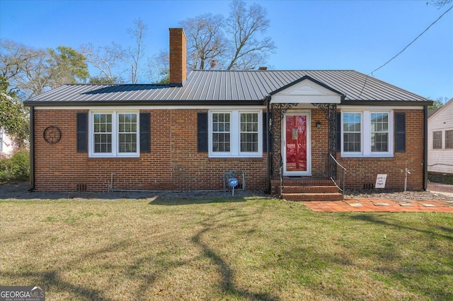 view of front facade featuring metal roof, brick siding, a chimney, and a front lawn