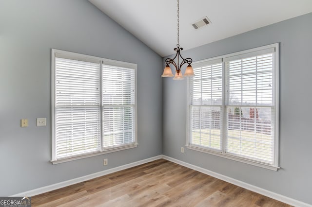 unfurnished dining area featuring visible vents, a notable chandelier, light wood-style flooring, baseboards, and lofted ceiling