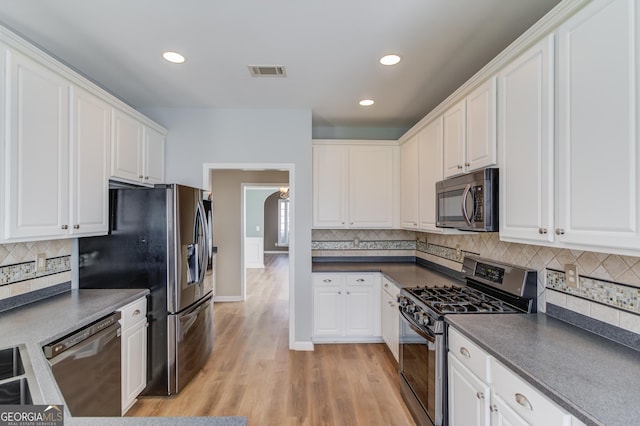 kitchen with white cabinetry, dark countertops, visible vents, and appliances with stainless steel finishes