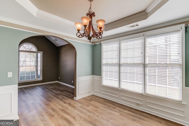 unfurnished room with visible vents, arched walkways, a raised ceiling, and a notable chandelier