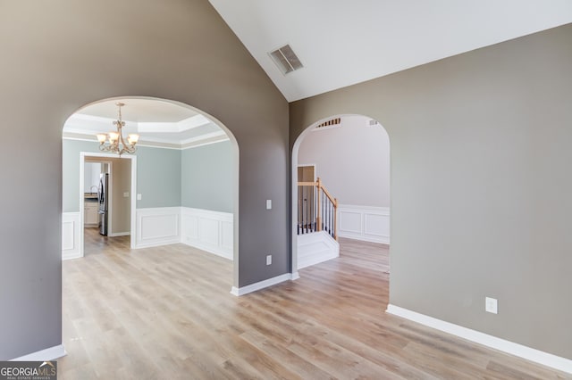 empty room with visible vents, arched walkways, and light wood finished floors