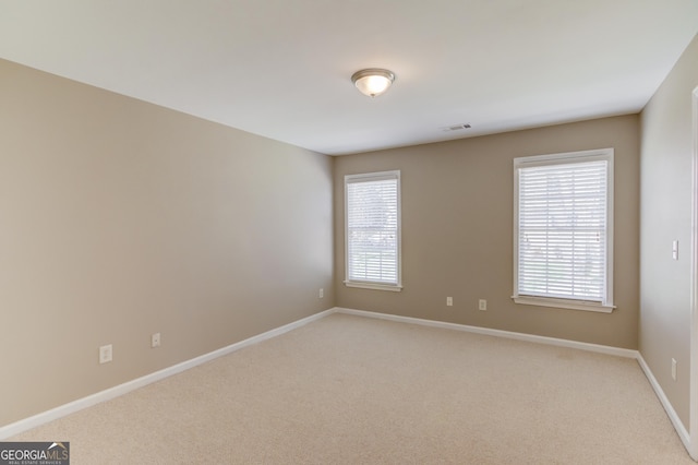 unfurnished room with plenty of natural light, baseboards, visible vents, and light carpet