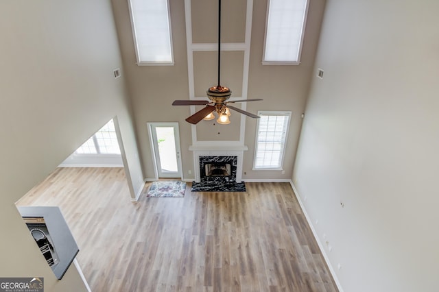 unfurnished living room with visible vents, baseboards, ceiling fan, a fireplace, and wood finished floors