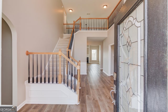 entryway with stairway, baseboards, arched walkways, and wood finished floors