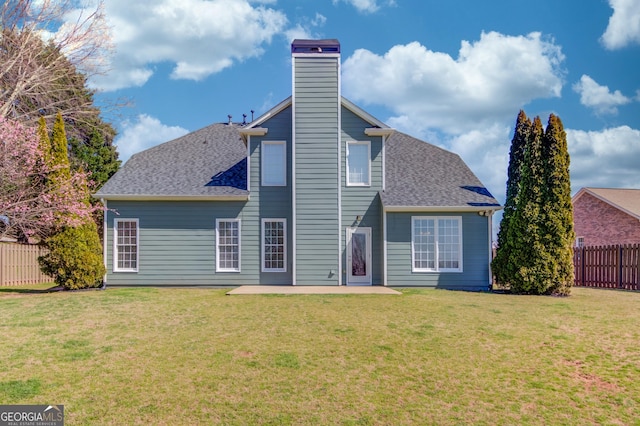 rear view of house with a patio, fence, roof with shingles, a chimney, and a lawn