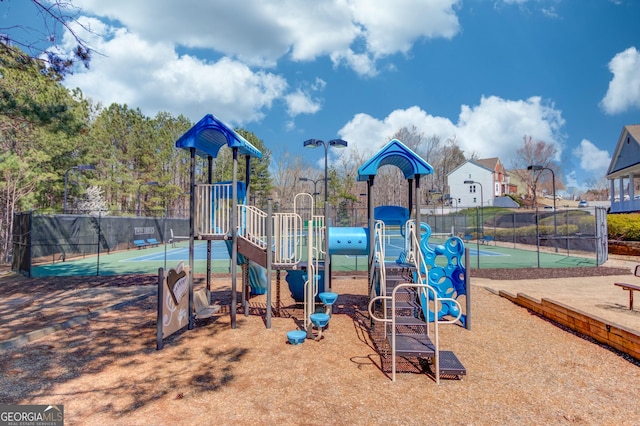 community play area featuring a tennis court and fence