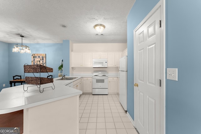 kitchen with visible vents, a sink, white appliances, a peninsula, and light countertops