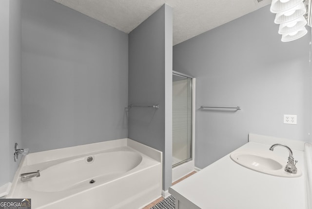 full bath featuring a bath, a stall shower, a textured ceiling, and a sink