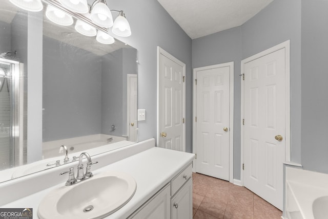 bathroom featuring tile patterned flooring, a garden tub, vanity, and a textured ceiling