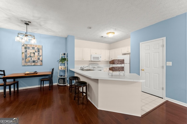 kitchen with white appliances, a breakfast bar area, light countertops, and wood finished floors