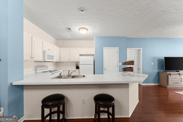 kitchen with visible vents, light countertops, a peninsula, white appliances, and a sink