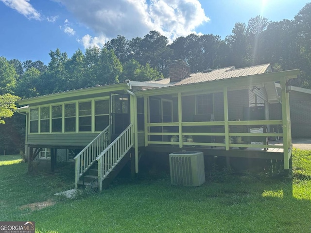 back of house featuring central air condition unit, a chimney, and a sunroom