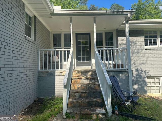 entrance to property with covered porch and brick siding