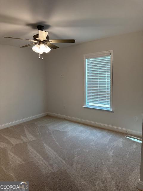 carpeted empty room with a ceiling fan and baseboards