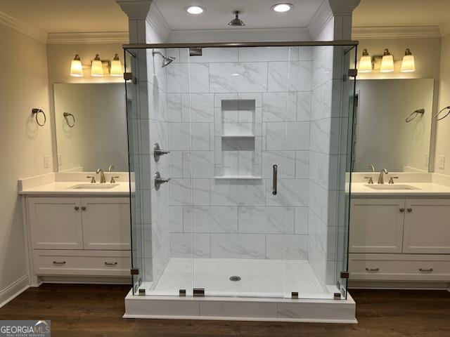 bathroom featuring crown molding, wood finished floors, a stall shower, and a sink