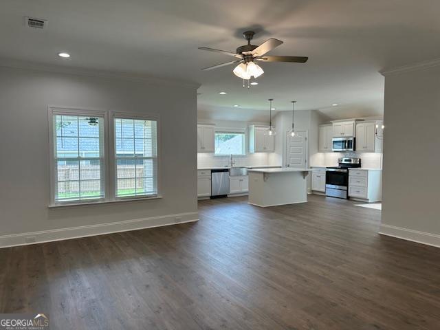 unfurnished living room with ceiling fan, baseboards, dark wood-style flooring, and ornamental molding