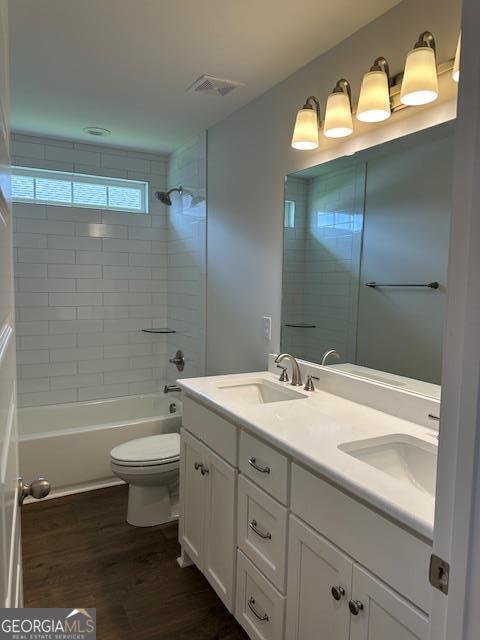 full bathroom featuring double vanity, wood finished floors, toilet, and a sink