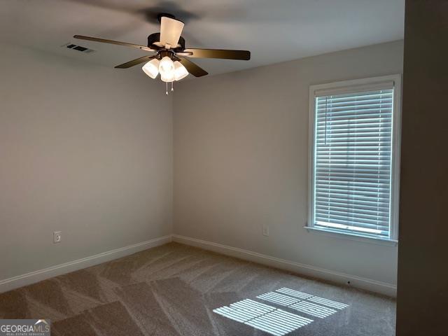 empty room featuring visible vents, baseboards, carpet floors, a wealth of natural light, and a ceiling fan