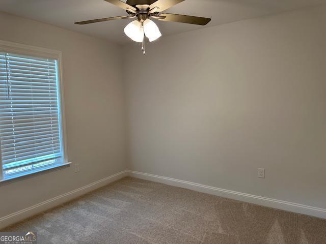 unfurnished room featuring a ceiling fan, baseboards, and light carpet