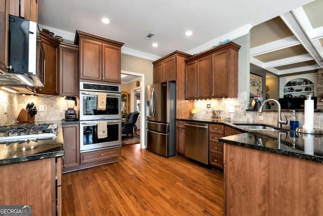 kitchen with visible vents, dark wood finished floors, dark stone counters, a sink, and appliances with stainless steel finishes