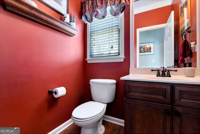 half bath featuring toilet, vanity, baseboards, and wood finished floors