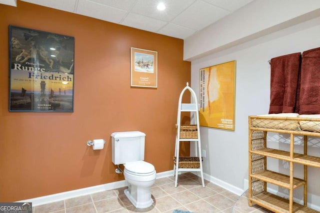 bathroom featuring tile patterned floors, baseboards, a paneled ceiling, and toilet