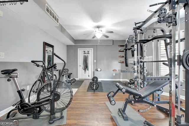 exercise area with baseboards, wood finished floors, visible vents, and ceiling fan