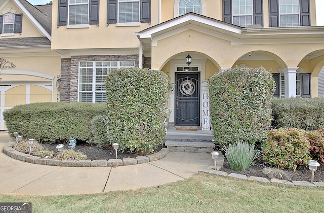 property entrance featuring stucco siding and stone siding