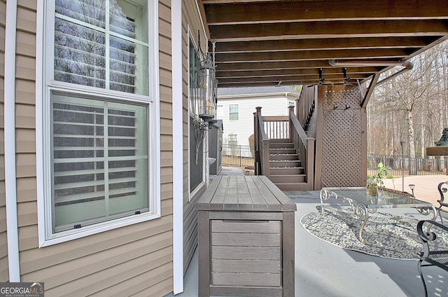 view of patio / terrace with stairway, outdoor dining space, and fence