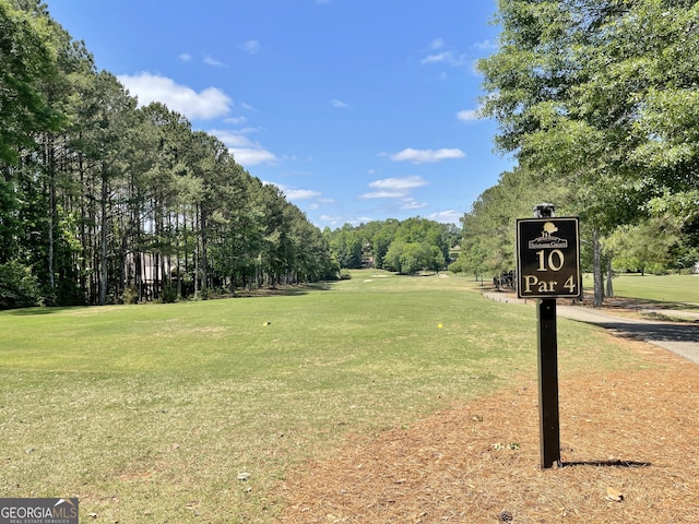 view of property's community with a lawn and view of wooded area